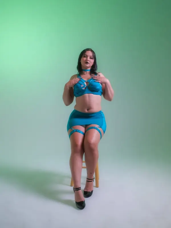 Lexie Anne in teal lingerie standing against a mint backdrop