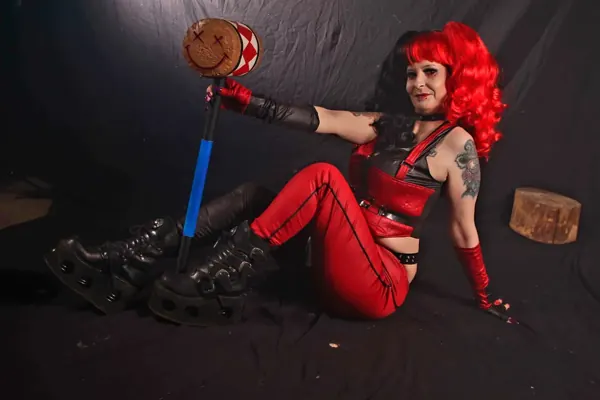 Selina Dark in a red wig and red outfit lounging on a dark set